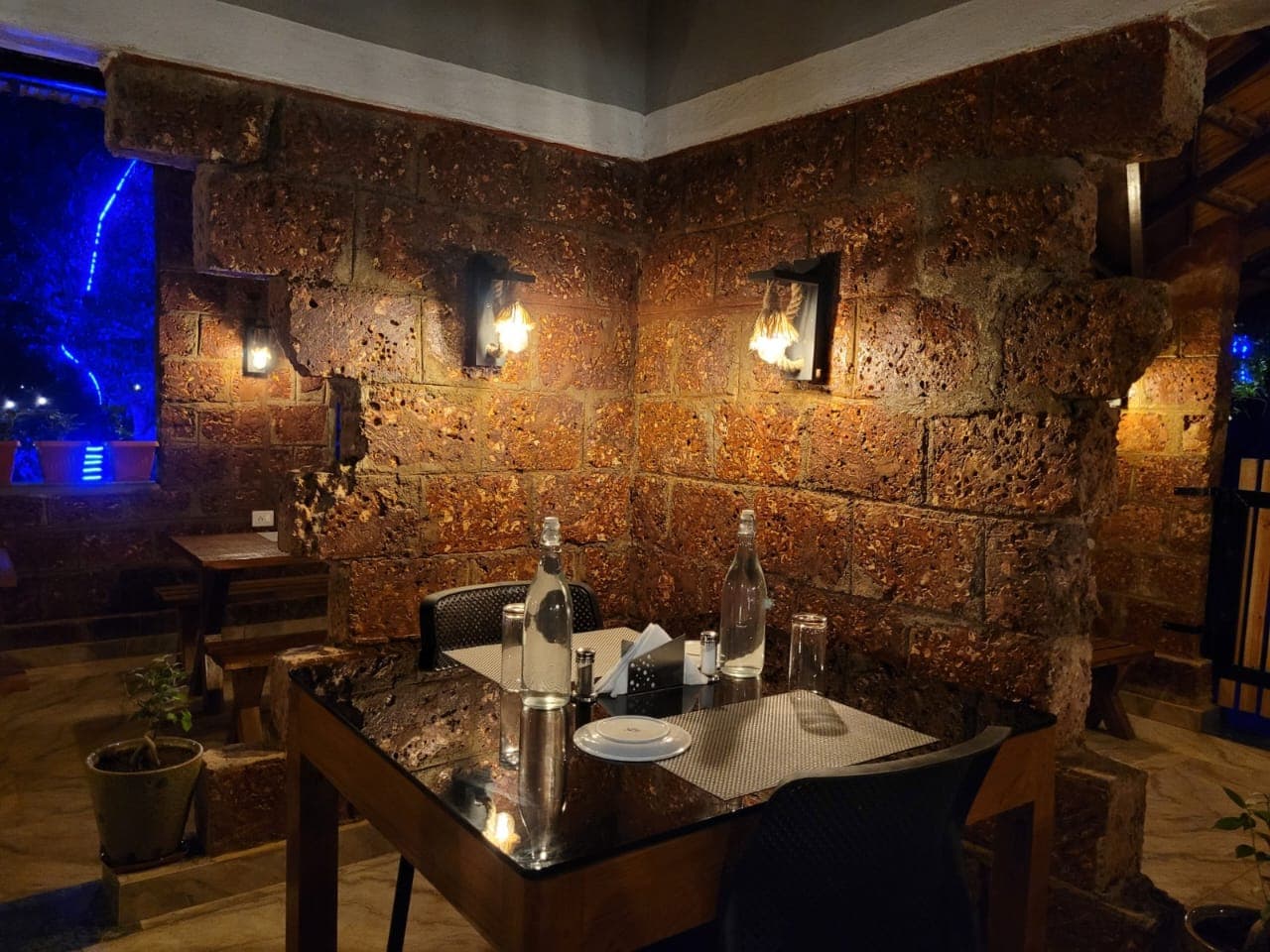 Evening table laid at Dandelion Kitchen, with laterite stone walls and warm lamplight